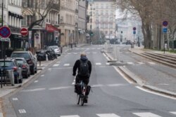 A man rides his bicycle along an empty street in Paris, on March 20, 2020 as a strict lockdown comes into effect to stop the spread of the COVID-19 in the country.