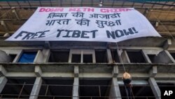 A model head in the likeness of Chinese President Xi Jinping is hung upside down beneath a large banner from a building by Tibetan activists during a protest in Dharmsala, India, Thursday, July 23, 2020. Activists from Students for a Free Tibet…