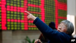 FILE - An investor gestures in front of the stock price monitor at a private securities company in Shanghai, China. 