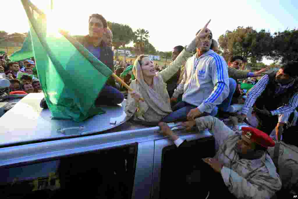Aisha Gaddafi, daughter of Libya's leader Muammar Gaddafi, holds a Libyan flag as she greets supporters at Bab Al-Aziziyah in Tripoli March 19, 2011. Thousands of Libyans packed into Muammar Gaddafi's heavily fortified Tripoli compound on Saturday to form