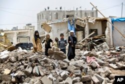 A boy and his sisters watch graffiti artists spray on a wall, commemorating the victims who were killed in Saudi-led coalition airstrikes in Sanaa, Yemen, May 18, 2015.