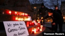 Una persona enciende una vela en una vigilia organizada por el grupo activista #wirgebendenToteneinGesicht (Le damos un rostro a los muertos) en honor a los muertos por COVID-19, en Berlín, Alemania, el 13 de diciembre de 2020. 