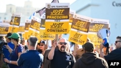 FILE - UPS workers hold placards at a rally held by the Teamsters Union on July 19, 2023 in Los Angeles, California, ahead of an August 1st deadline for an agreement on a labor contract deal. (Photo by Frederic J. BROWN / AFP)