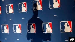 FILE - A MLB logo backdrop is seen at a press conference in Phoenix, Arizona, Feb. 23, 2015.