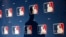 FILE - The shadow of MLB Commissioner Rob Manfred is projected on an MLB logo backdrop in Phoenix, Arizona, Feb. 23, 2015.