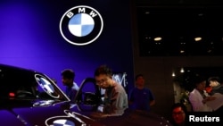 FILE - Visitors look at vehicles at the BMW booth at the Beijing International Automotive Exhibition, or Auto China 2024, in Beijing, April 25, 2024. The company has cut its profit margin forecast in part because of sluggish demand in China.