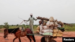 FILE - A Chadian cart owner transports belongings of Sudanese people who fled the conflict in Sudan's Darfur region, while crossing the border between Sudan and Chad in Adre, Chad August 4, 2023. 