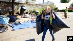 Un trabajador de asistencia ayuda a limpiar u cammpamento de desamparados en Portland, Oregón, el 27 de julio de 20233.