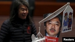 Lawmaker Leung Kwok-hung, demanding better welfare for the elderly, carries a mocking portrait of Hong Kong Financial Secretary John Tsang before Tsang's annual budget report at the Legislative Council in Hong Kong, Feb. 24, 2016.