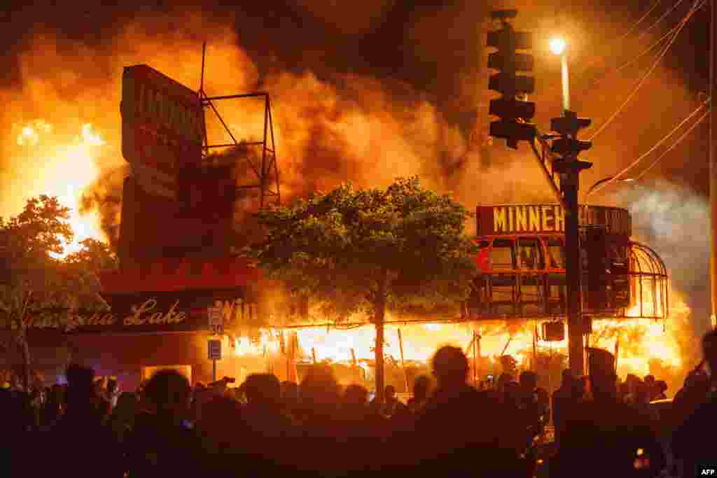 Protesters gather in front of a liquor store in flames in Minneapolis, Minnesota, May 28, 2020, during a protest over the death of George Floyd, an unarmed black man who died after a police officer kneeled on his neck for several minutes. 