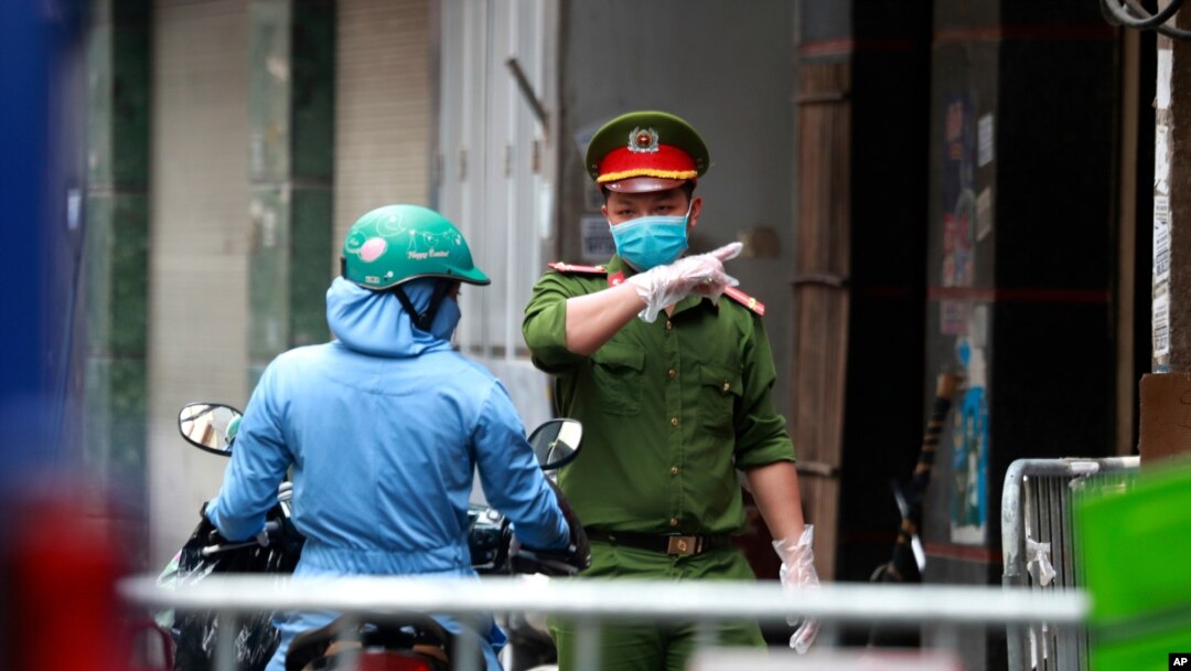 Seorang polisi berbicara dengan seorang perempuan di pintu masuk barikade di mana salah satu warganya diduga memiliki Covid-19 di Hanoi, Vietnam, Rabu, 29 Juli 2020. (Foto: dok).