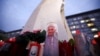 A candle with an image of Pope Francis lies next to the statue of the late Pope John Paul II, outside the Gemelli Hospital, where Pope Francis was admitted for treatment, in Rome, Feb. 20, 2025.