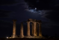 The super moon rises in the sky in front of the Apollo's temple about 80 kilometers southwest of Athens on Tuesday, April 7, 2020.