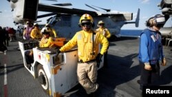 Soldiers are seen next to the U.S. Marine Corps MV-22 Osprey aircrafts on the flight deck of the USS Wasp (LHD 1) amphibious assault carrier during their operation in the waters off Japan's southernmost island of Okinawa, March 23, 2018.