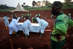 Workers lower a coffin containing the body of a suspected COVID-19 victim into a grave during a burial at the special section of Pondok Ranggon cemetery during coronavirus outbreak, in Jakarta, Indonesia, Sept. 24, 2020.