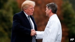 Presiden AS Donald Trump (kiri) berjabat tangan dengan Dokter Gedung Putih, Laksamana Muda Ronny Jackson saat pemeriksaan kesehatan di rumah sakit Walter Reed di Bethesda, Maryland, 12 Januari lalu. 