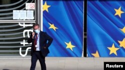 A man wearing a protective mask walks past the EU Commission headquarters amid the coronavirus outbreak, in Brussels, Belgium, Sept. 18, 2020. 