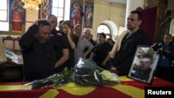 Relatives of slain policeman Sasho Samoilovski mourn next to his coffin covered in Macedonian flag inside a church in the town of Tetovo, Macedonia, May 10, 2015.