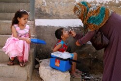 FILE - A boy receives polio vaccine drops, during an anti-polio campaign, in a low-income neighbourhood in Karachi, Pakistan.