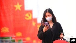 FILE - A woman wearing a face mask looks at her phone in Hanoi, Vietnam, Jan. 23, 2021. Vietnam says it has discovered a new coronavirus variant that’s a hybrid of strains first found in India and the U.K. (Reuters)