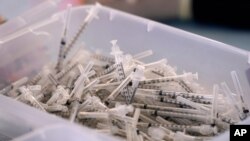 FILE - In this file photo dated Monday, March 29, 2021, A bin of used syringes inside a trailer during a mass vaccination event in Metairie, outside New Orleans, USA.