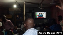 Des Congolais regardent la télévision pendant que le Président Félix Tshisekedi prononce son discours à Kinshasa, le 6 décembre 2020.