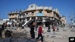 Palestinos pasan junto a edificios destruidos por un bombardeo israelí en el campo de refugiados de Nusseirat, en la Franja de Gaza, el 16 de enero, mientras la situación se agrava. 