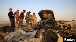 FILE - Iraqi security forces inspect the site of a bomb attack at a police checkpoint on a highway near the southern Iraqi city of Nassiriya, Sept. 14, 2017. 