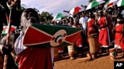 A traditional Burundian drummer dances with a shield and staff as he welcomoes a ruling party leader during a political rally at a sports field in Bujumbura, 11 May 2010