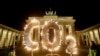 FILE - Activists of the environment organization Greenpeace protest with CO2 letters illuminated with flames in front of the Brandenburg Gate against the climate change in Berlin, Germany, May 6, 2021. 