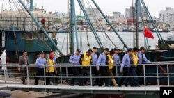 Chinese fishermen, wearing yellow jackets, are led by South Korean police officers after they were arrested at a port in Mokpo, South Korea, Wednesday, Oct. 17, 2012. The South Korean coast guard on Tuesday fatally shot a Chinese fisherman with a rubber b