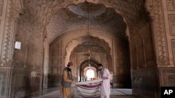 FILE —Workers clean the carpet in the historical 'Badshahi' mosque in preparation for the upcoming Lahore, Pakistan, March 9, 2024.