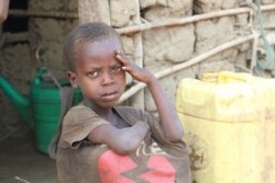 A young boy sits outside his small house in a village on the outskirts of Burundi capital Bujumbura, July 6, 2019.