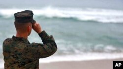 A U.S. Marine Corps officer uses binoculars to search for debris of two helicopters missing off the coast of Hawaii, in Haliewa Beach Park, Hawaii, Jan. 15, 2016.