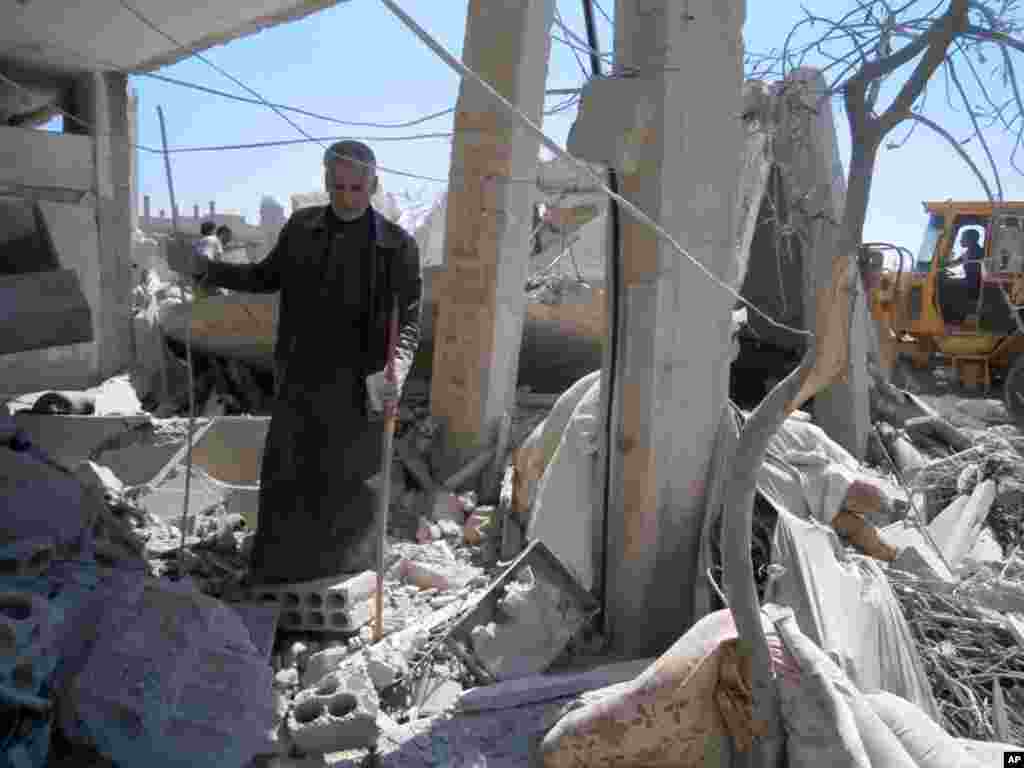 This citizen journalism image provided by Qusair Lens shows a man checking his house that was damaged by an airstrike, Qusair, Homs, Syria, May 21, 2013.