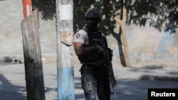 A police officer stands guard near a site where alleged gang members were set on fire by a crowd of people, when trying to drive away, in Port-au-Prince, Haiti April 24, 2023. 