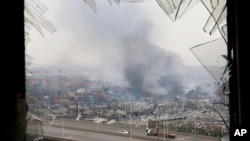 FILE - a window shattered by the shockwaves frame the site of an explosion at a warehouse in northeastern China's Tianjin municipality, August 14, 2015.