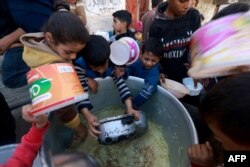 Palestinska djeca uzimaju hranu iz humanitarne pomoći u Rafi, 6. decembar 2023. (foto: AFP/ MOHAMMED ABED)