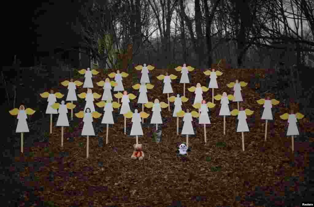 Twenty-seven wooden angel figures are seen placed in a wooded area beside a road near the Sandy Hook Elementary School for the victims of a school shooting in Newtown, Connecticut, December 16, 2012. 