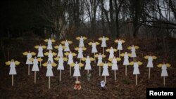 Twenty-seven wooden angel figures are seen placed in a wooded area beside a road near the Sandy Hook Elementary School for the victims of a school shooting in Newtown, Connecticut, December 16, 2012. 