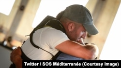 Un membre des équipes de l’ONG SOS Méditerranée embrasse un des cinq migrants après la décision de ceux-ci de repartir en Tunisie, à bord du navire humanitaire Aquarius, sur la Méditerranée, 25 août 2018. (Twitter/ SOS Méditerranée)