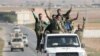 Turkey-backed Syrian rebel fighters gesture as they ride on a vehicle near the border town of Tal Abyad, Syria, Oct. 22, 2019.