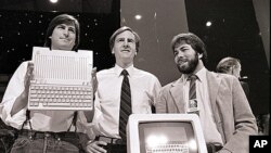 Steve Jobs (kiri), John Sculley (tengah), presiden dan CEO Apple, serta Steve Wozniak, salah satu pendiri Apple, memperlihatkan komputer Apple II di San Francisco pada 4 April 1984. (AP)