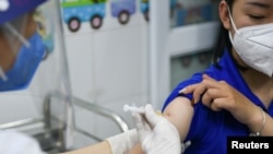 FILE - A woman receives a vaccine as Vietnam starts its official rollout of AstraZeneca's coronavirus vaccine for health workers, at Hai Duong Hospital for Tropical Diseases, Hai Duong province, Vietnam, March 8, 2021. 