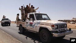 Anti-Gaddafi fighters travel on a vehicle at a strategic checkpoint, after returning from the north of the besieged city of Bani Walid, Libya, September 23, 2011.