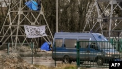 Un membre du réseau Pas de frontières descend d'un poteau électrique après l'installation d'une tente, à Calais, France, 2 février 2018.