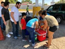 Central American migrants line up for community-donated food and drinks near the Puente Numero I International Bridge in Nuevo Laredo, Mexico. (R. Taylor/VOA)