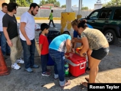 Central American migrants line up for community-donated food and drinks near the Puente Numero I International Bridge in Nuevo Laredo, Mexico. (R. Taylor/VOA)
