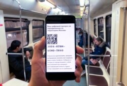 In this photo taken April 14, 2020, a man shows electronic passes with a QR-code displayed on smartphone screen as he rides Moscow's subway.