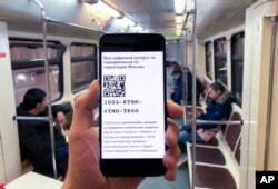 In this photo taken April 14, 2020, a man shows electronic passes with a QR-code displayed on smartphone screen as he rides Moscow's subway.